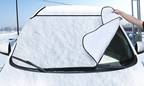 Windscreen frost cover fitted over a snow-covered car windscreen, being lifted off